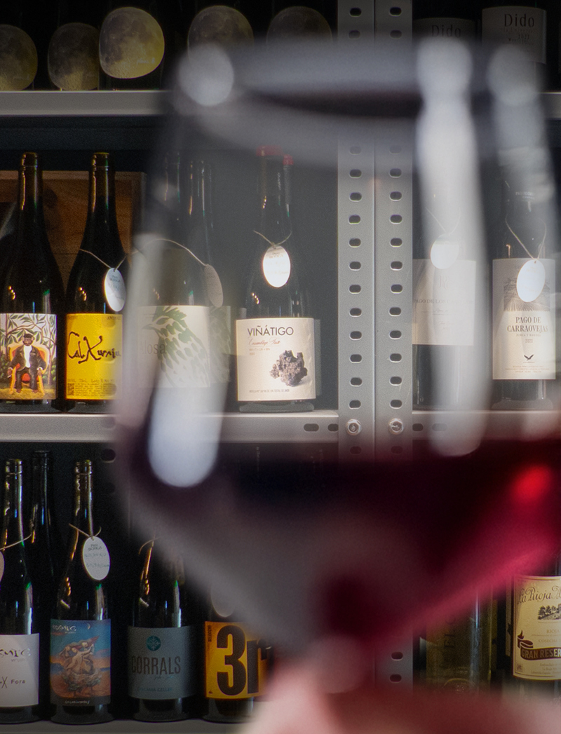Primer pal d'una copa de vi amb l'estanteria de vins al fons.